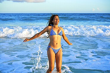 Latin beautiful bikini girl happy jumping in Caribbean beach sunset