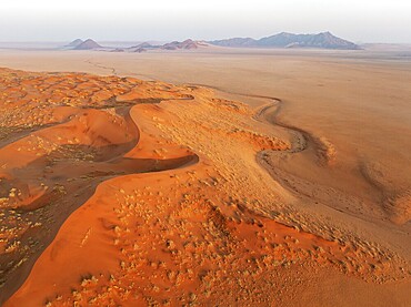 Sand dunes and isolated mountain ridges at the edge of the Namib Desert. Aerial view. Drone shot. Namibia