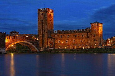 Majestic castle with bridge illuminated against the night sky with mirror-smooth river, at the blue hour, above the river Adige, Museo di Castelvecchio, Ponte Scaligero, Verona, Veneto region, Italy