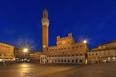 Illuminated square at night with a central historic building and the Torre del Mangia tower, Piazza del Campo, Siena, Tuscany, Italy