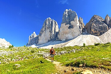 Tourist enjoying a summer hike on a scenic trail leading to the majestic tre cime di lavaredo peaks in the dolomites, Italy