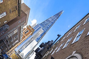 Low angle view of the shard skyscraper dominating the skyline above traditional brick buildings in London, uk, highlighting the contrast between old and new