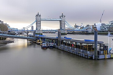 Tower bridge standing majestically over the river thames with boats moored at a pier, showcasing the iconic London landmark