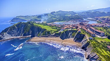 Breathtaking aerial perspective of zumaia's dramatic cliffs, golden beaches, and charming town nestled along the vibrant bay of biscay coastline in the basque country, Spain.