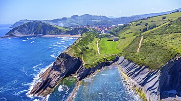 Aerial perspective captures the stunning beauty of zumaia's flysch cliffs meeting the vibrant blue ocean on a sunny summer day, Spain.