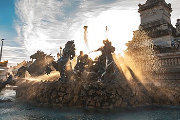 The majestic monument aux girondins fountain, located in place des quinconces, bordeaux, is illuminated by the golden rays of the setting sun