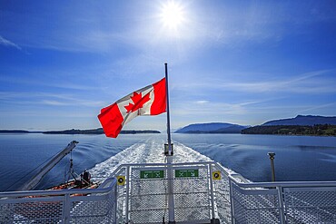 A Canadian flag flying on the stern of a BC Ferries vessel sailing from Alert Bay to Port McNeill, British Columbia, Canada