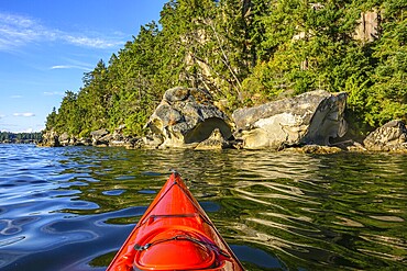 A bright red kayak along the rocky western shore of Gabriola Island, British Columbia, Canada