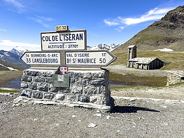 In the foreground signpost to the pass summit of the highest navigable alpine pass Col de l'Iseran 2764 2770 metres high, Iseran Pass, Iseran, below direction signs to Lanslebourg and Bourg Saint Maurice, in the background chapel Chapelle Notre-Dame-de-Toute-Prudence, Col de l'Iseran, departmental road D902, Route des Grandes Alpes, Département Savoie, Region Auvergne-Rhône-Alpes, Graian Alps, France