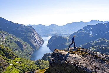 Mountaineer, young man hiking in front of mountain landscape, fjord Trollfjord and mountains, hike to Trollfjord Hytta, at Trollfjord and Raftsund, Lofoten, Nordland, Norway