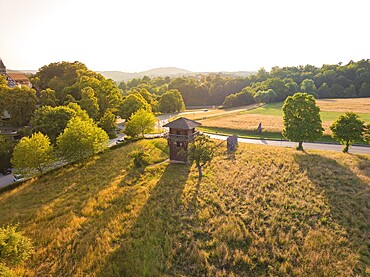 A wooden tower stands in a spacious meadow under the warm evening sun, event and wedding location Lorch Monastery, Lorch, Germany