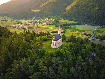 Church above a valley with a village surrounded by mountains at dusk