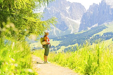 Person walking on a path with a view of mountains on a sunny day, Alpe di Siusi, Dolomites, South Tyrol, Italy