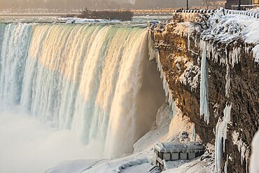 The Canadian Horseshoe Falls in on a cold winters day with snow and ice covering the railings and walkway in Niagara Falls, Ontario, Canada, North America