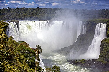 Massive waterfall with rising mist, surrounded by tropical vegetation, The Iguazu Falls between Argentina and Brazil