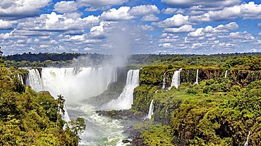 Waterfalls in the dense jungle, surrounded by lush greenery under a cloudy sky, The Iguazu Falls between Argentina and Brazil