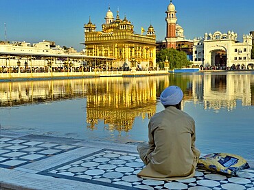 Devout Sikh in front of the Harmandir Sahib or Hari Mandir (temple of God), usually called the Golden Temple, on an island in the artificial lake, the Amrit Sarovar. Sikh sanctuary in Amritsar, Punjab, India