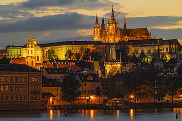 The evening skyline of Prague Castle with illuminated cathedral and the Vltava River, Prague, Czech Republic