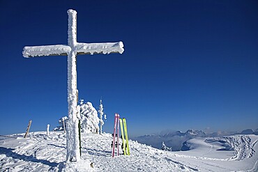 Snow-covered summit cross and touring skis on the summit of the Reuterwanne. in the distance the Tannheimer mountains, Allgäu Alps, Jungholz, Tyrol, Austria