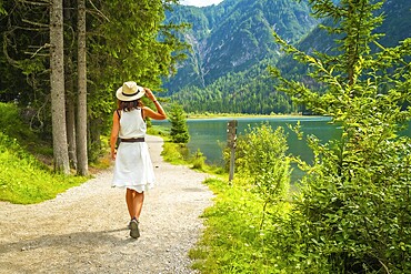Tourist walking on a path near lake dobbiaco, enjoying the summer landscape in the dolomites