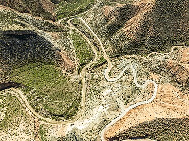 Winding road in the desert, surrounded by colorful canyons and gorges, aerial view, Gorafe Desert, UNESCO Granada Geopark, Granada province, Andalusia, Spain