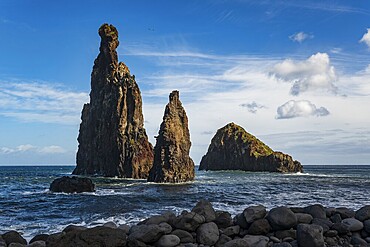 Dramatic rock formations rise out of the sea on the rocky beach of Ribeira da Janela, surrounded by sky, Madeira, Portugal