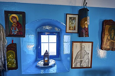 Blue painted wall with various religious pictures around a small window, chapel, church, Agios Isidoros, rocky islet, Gourna Bay, Kokkali, Leros, Dodecanese, Greek Islands, Greece