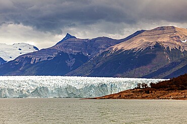 Impressive glacier front with dramatic sky and mountainous backdrop, The Perito Moreno glacier in Argentina