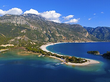View of a beach with a peninsula surrounded by mountains and blue sea under a clear sky with clouds, aerial view, Fethiye, Muğla, Mugla, Aegean Sea, Turkey