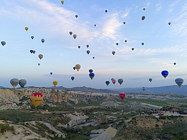 Many colourful hot air balloons float over a vast Turkish landscape in the early morning, aerial view, Göreme National Park, Göreme Tarihî Millî Parki, Nevsehir Province, Nevsehir, Cappadocia, Cappadocia, Kapadokya, Cappadocia, Central Anatolia, Turkey