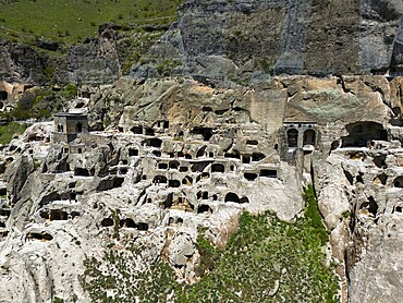 Caves lined up in a massive rock face, surrounded by green areas, aerial view, cave town, cave monastery, Vardzia, Vardzia, Samtskhe-Javakheti region, Samtske Javakheti, Lesser Caucasus, Georgia