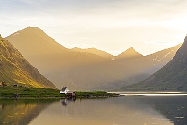 Landscape with sea and mountains on the Lofoten Islands. The fjord Flakstadpollen and some houses belonging to the village of Flakstad. At night during the midnight sun. Flakstadoya, Lofoten, Norway