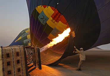 In order to get ready for the take-off, the pilot inflates the balloon with hot air by activating the burner. At dawn. Namib Desert, Kulala Wilderness Reserve, Namibia