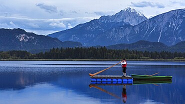 Alphorn players on a raft with mountains in the background with calm water, Tannheimer Berge, Hopfensee, Landkreis Ostallgäu, Bavaria, Germany