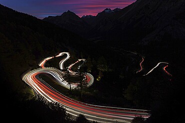 Winding mountain road at night with glowing light traces due to long exposure, Maloja Pass, Canton Graubünden, Switzerland
