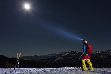 Night scene at full moon of a skier in the moonlight in front of a mountain scenery, with shining headlamp, summit Reuterwanne, in the background the Tannheimer mountains, Allgäu Alps, Jungholz, Tyrol, Austria