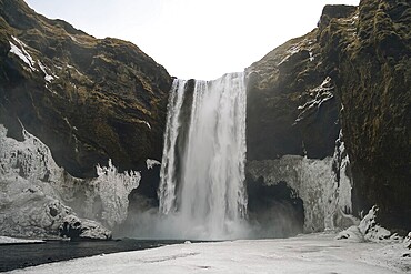 The mighty Skogafoss waterfall in winter. Roaring masses of water meet ice and rock. Skogar, Rangarping eystra, Iceland