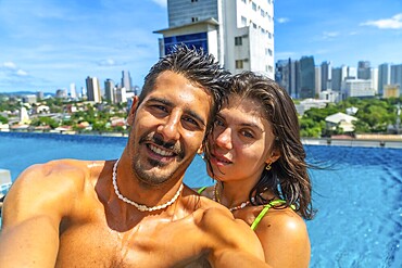 Tourists enjoying holidays in a rooftop swimming pool in cebu city, philippines, taking a selfie with cityscape in the background