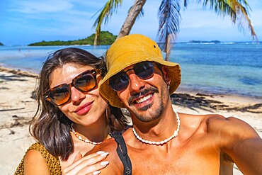 Tourists enjoying summer holidays on lakdayan beach, coron island, taking a selfie with turquoise sea and palm trees in the background