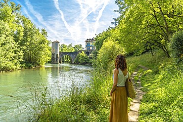 Woman enjoying summer vacations in french countryside admiring the medieval bridge and tower of sauveterre de bearn in the pyrenees atlantiques