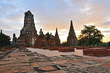 Serene buddha statues sit amidst crumbling temple ruins, bathed in the golden light of a beautiful sunset in thailand