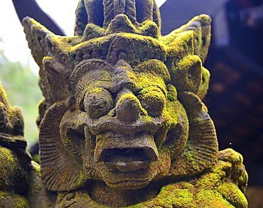 Close up of a weathered traditional balinese stone statue covered in moss, showcasing the rich cultural heritage of bali