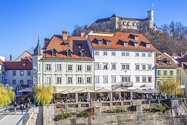 View of buildings along Ljubljanica River and Castle visible in background, Ljubljana, Slovenia, Europe