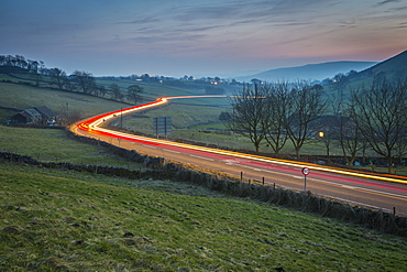 View of vehicle trail lights on A623 at Sparrowpit at dusk, Peak District National Park, Derbyshire, England, United Kingdom, Europe