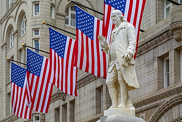 View of Benjamin Franklin statue and US flags in front of former Old Post Office Pavilion, Washington D.C., United States of America, North America