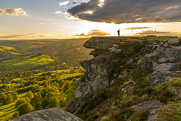 View of lone piper at at sunset on Curbar Edge, Curbar, Hope Valley, Peak District National Park, Derbyshire, England, United Kingdom, Europe