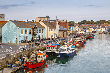 View of boats in the Old Harbour and quayside houses at dusk, Weymouth, Dorset, England, United Kingdom, Europe