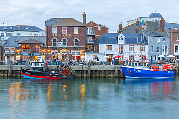 View of boats in the Old Harbour and quayside houses at dusk, Weymouth, Dorset, England, United Kingdom, Europe