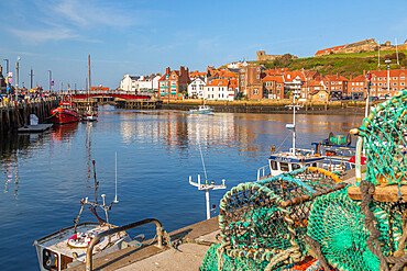 View of St. Mary's Church and fishing baskets, houses and boat on the River Esk, Whitby, Yorkshire, England, United Kingdom, Europe