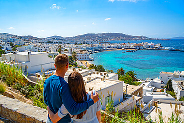 Young couple with elevated view of flour mills and town, Mykonos Town, Mykonos, Cyclades Islands, Greek Islands, Aegean Sea, Greece, Europe